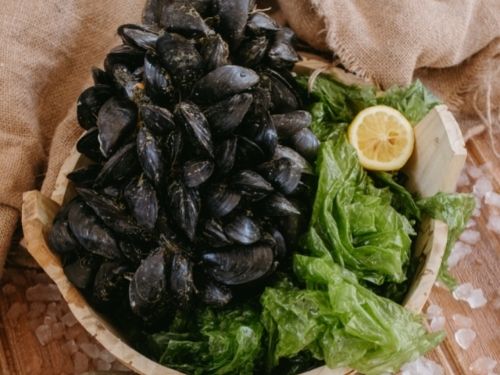 Mussels in a bowl with salad and lemon